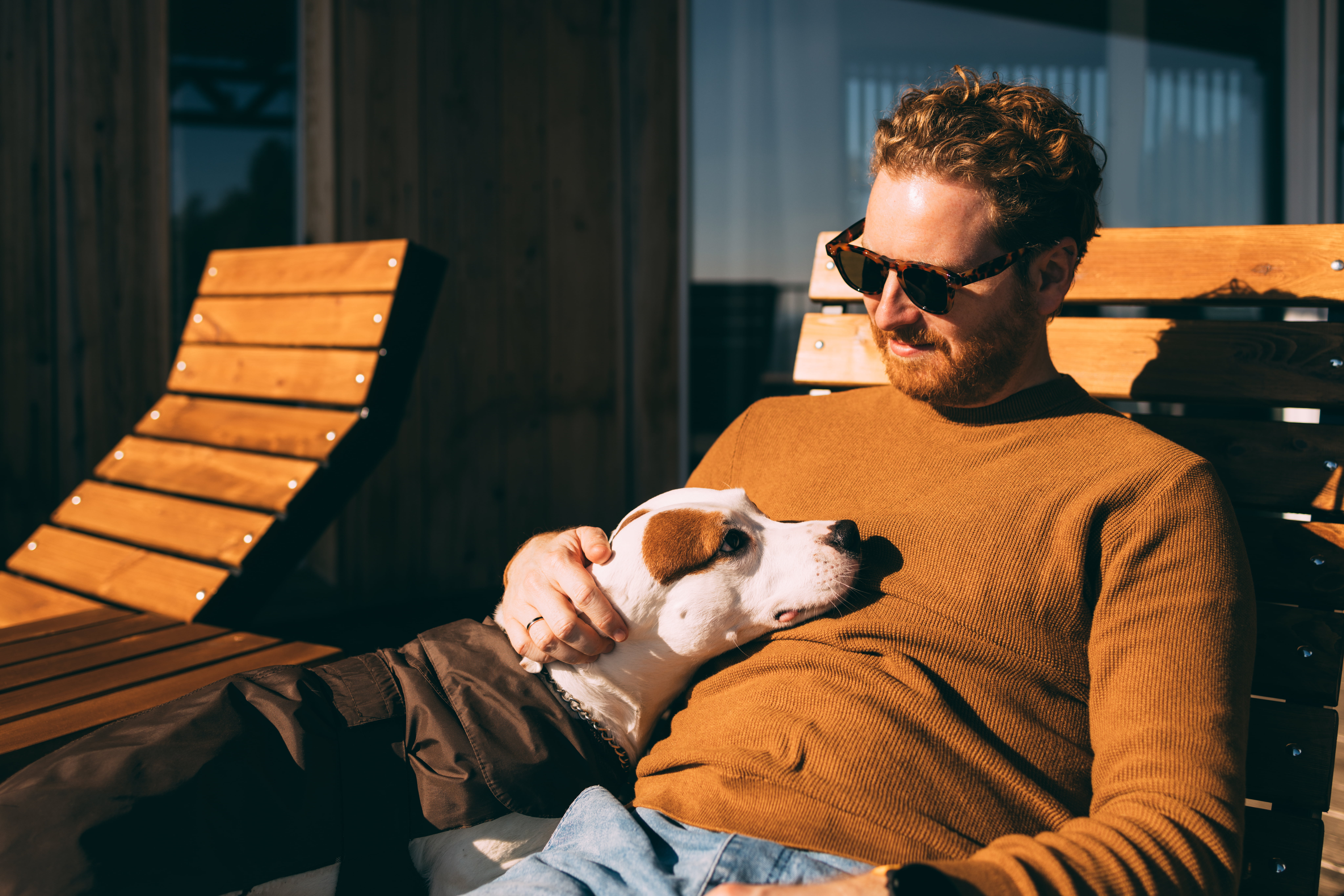 Mann sitter i solen med hund