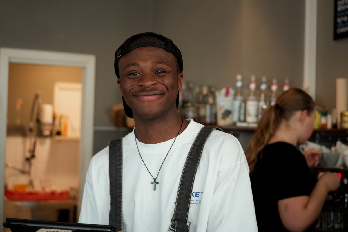 En blid og ung mann som jobber på en kafé