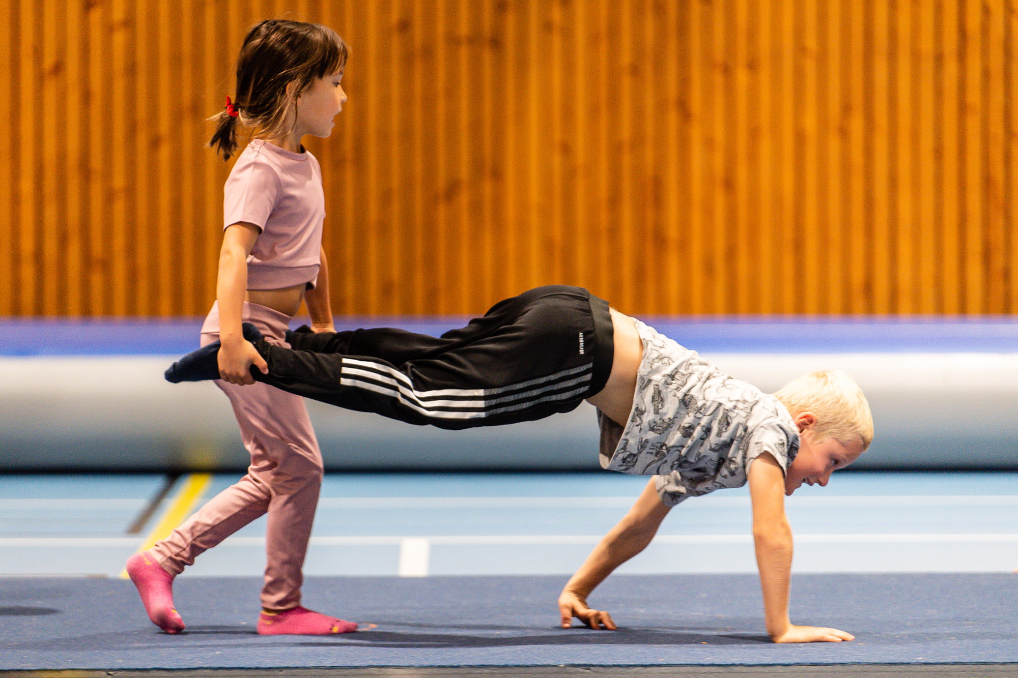 En ung jente holder beina til en ung gutt som går på armene